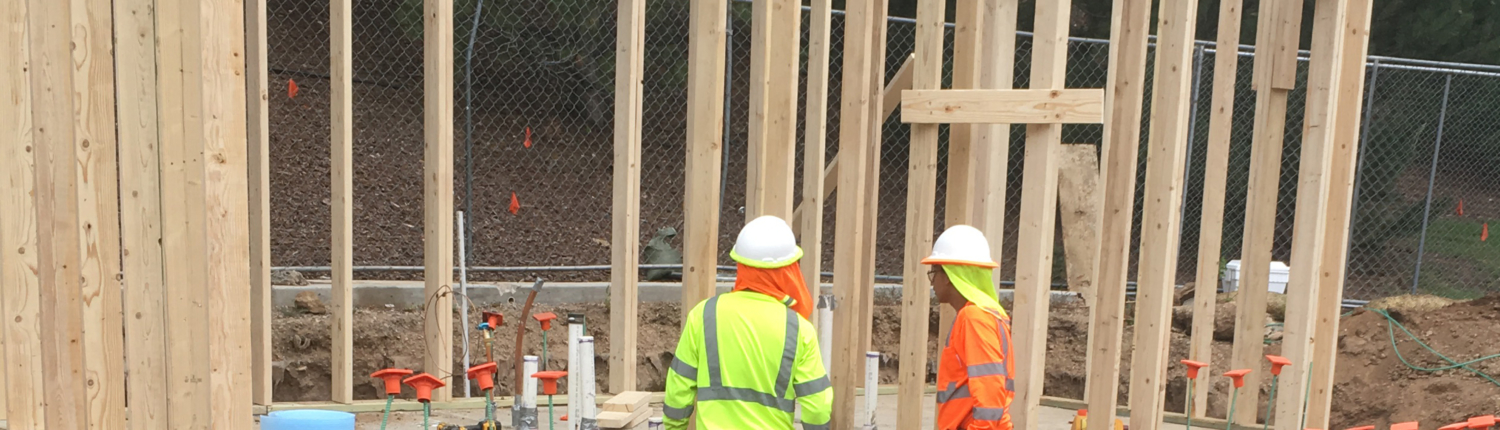 Construction workers standing in front of a building frame