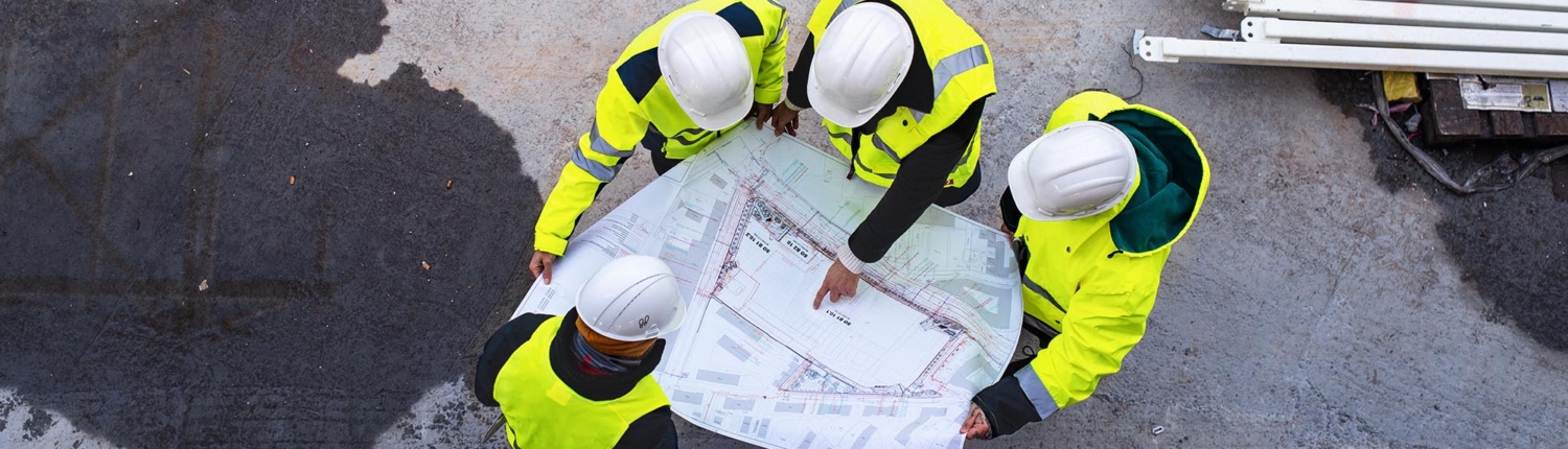 Image of construction workers pointing at construction blueprints.