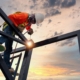 Image of a worker welding together a steel building structure.