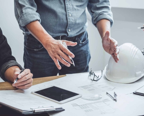 three workers talking over a table with plans and blueprints