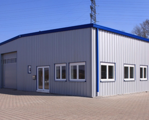 Side view of a grey steel building with blue roof